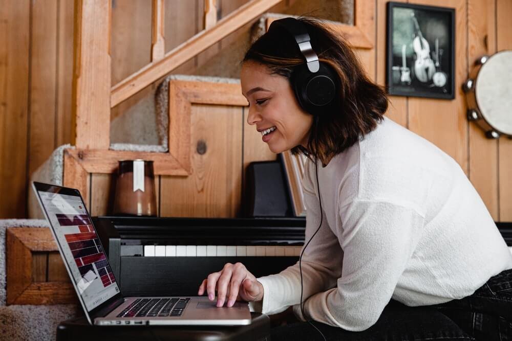 woman with headphones smiling at computer
